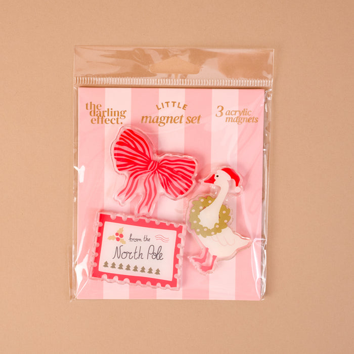 Tis the Season Little Magnet Set including three artistic fridge magnets: a red striped bow, a goose wearing a Santa hat and wreath, and a rectangular North Pole gift tag.