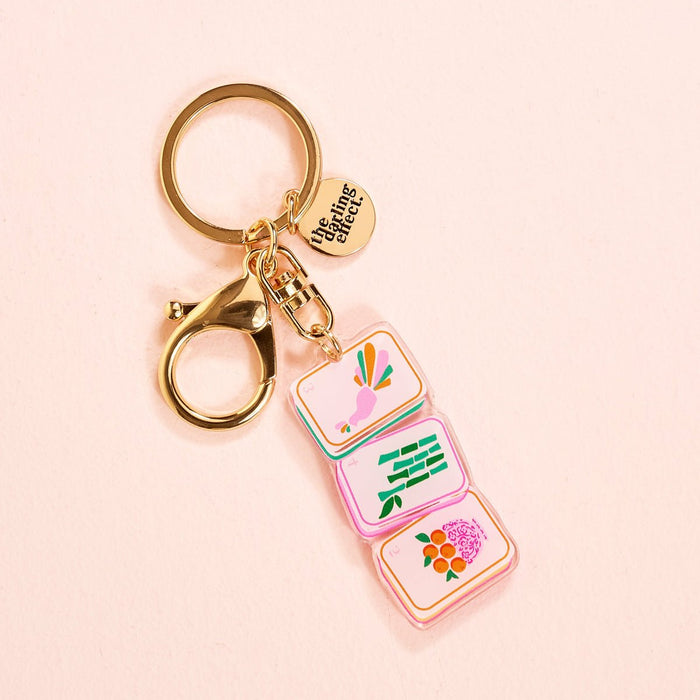 The Darling Effect’s Mahjong Tiles Acrylic Keychain features a lobster clasp, three colorful charms (bird, green bamboo, pink flower), and a round “unsung talents” tag—a stylish accessory for your bag or keys.