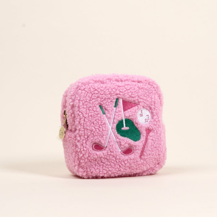 The Darling Effect’s Square The Golf Edit Teddy Pouch is a small pink sherpa pouch featuring embroidered golf clubs, a green patch, pink flag, white ball, and a round gold zipper pull—perfect for on-the-go organization.