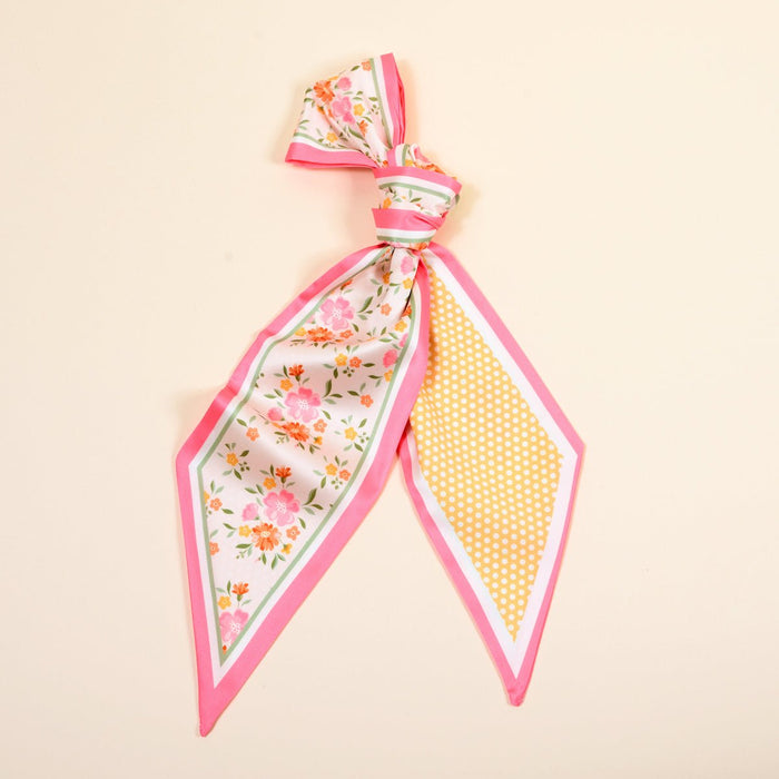 The Darling Effect's Endless Daydream Cream Twirl & Tie Scarf Accessory is a versatile silk scarf with pink edges, floral print on one end, and yellow polka dots on the other, all set against a light beige background.