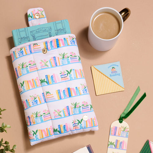 The Darling Effect’s "I’d Rather Be Reading" Corner Keeper Fabric Bookmark is displayed on a tan surface with a book-themed pouch, coffee, a “Sssh! I'm reading” note, another fabric bookmark, and green leaves—a perfect gift for book lovers.