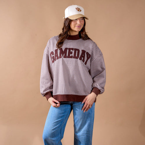A smiling woman with long dark hair wears a pink sweatshirt with green and white stripes and the word GOLF on the front, standing against a plain light background.