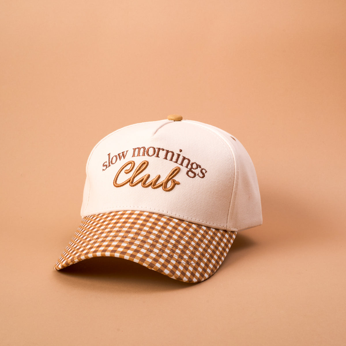 The Darling Effect’s Slow Mornings Club Classic Canvas Hat features “Slow Mornings Club” embroidered on the front and a brown-and-white checkered brim, all set against a beige background—a timeless accessory that’s perfect for everyday wear.