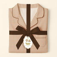 Folded brown and white Maple Gingham Sweet Dreams Pajama Shorts Set by The Darling Effect, tied with a dark brown ribbon and featuring a gift tag that reads “Slumber Party Pajama Set S,” displayed against a cream background—a perfect pajama gift set for cozy nights in comfortable pajamas.