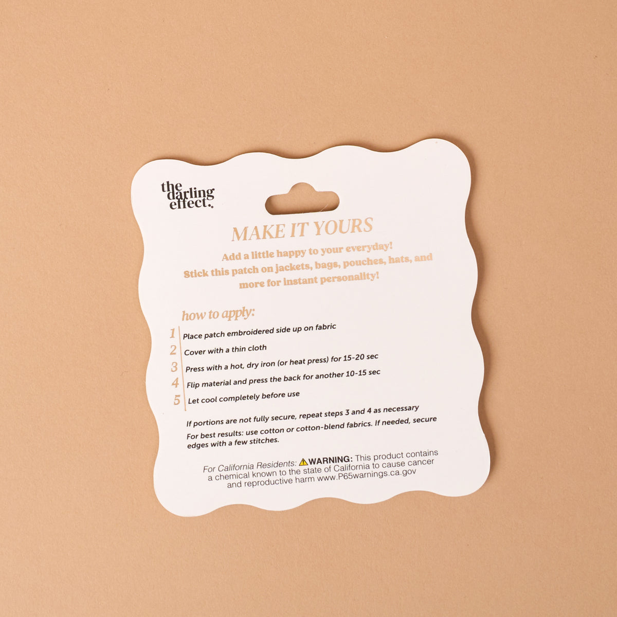 A scalloped-edge card on a tan background displays application instructions for The Darling Effect’s On Patch-Pumpkin Spice Season Mix & Match Iron patches, featuring colorful designs and outlining the steps to iron, peel, and cool, along with a warning about chemical exposure.