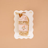 Add a splash of whimsy to your look with The Darling Effect’s Coffee Run Shape Up Claw Clip, designed as a charming whipped cream-topped drink complete with brown straws and subtle floral details. Perfect for crafting cute hairstyles, this playful hair accessory comes displayed on a scalloped-edged backing card set against a beige background.
