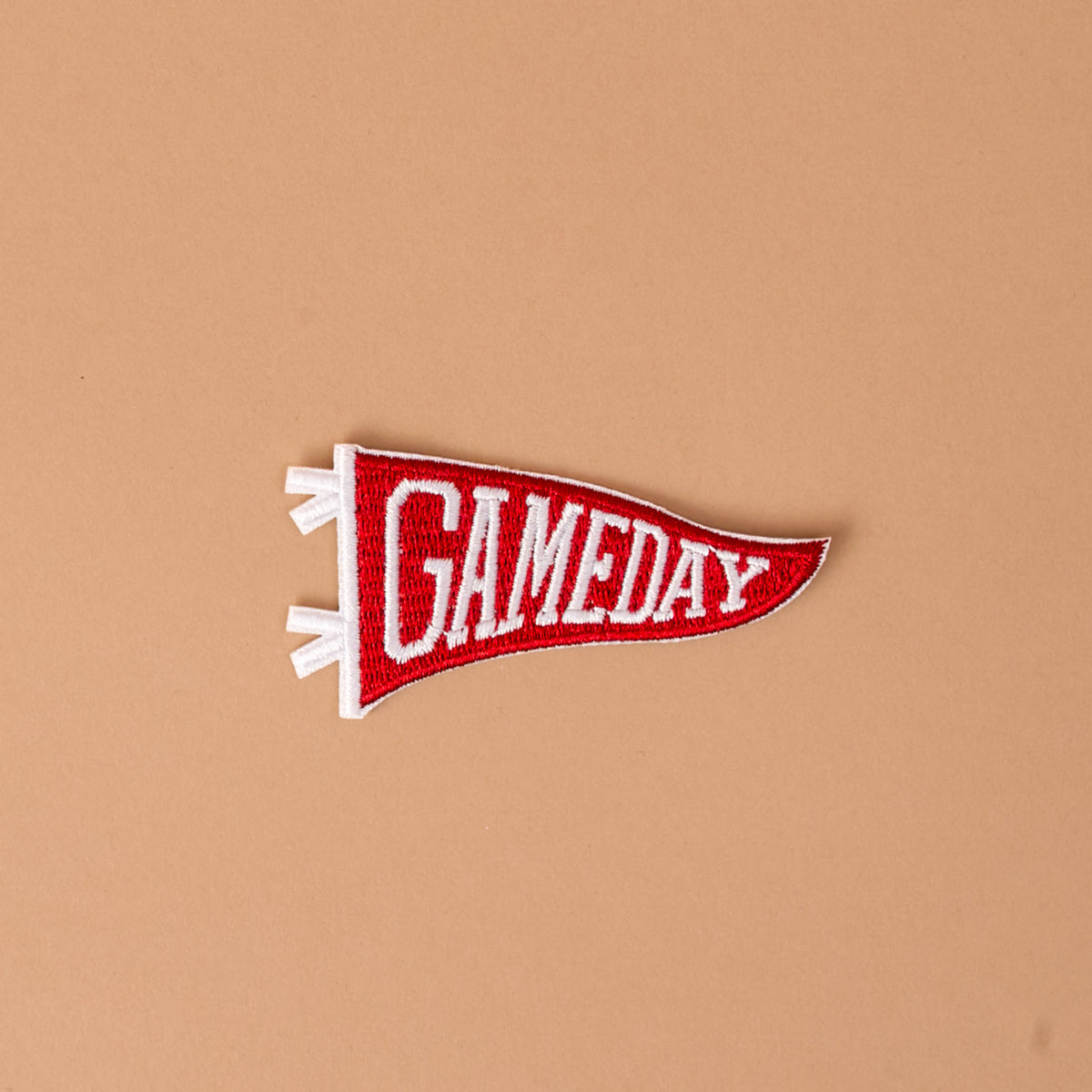 A burgundy and white embroidered "Gameday" patch from The Darling Effect, shown on a plain light brown background—perfect for fans of colorful designs who want to customize their look with this unique Mix & Match iron-on patch.