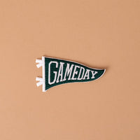 A Gameday Green Mix & Match Iron-On Patch by The Darling Effect, featuring bold green and white felt with the word GAMEDAY, is displayed on a simple beige background—perfect for customizing with colorful designs or additional patches.