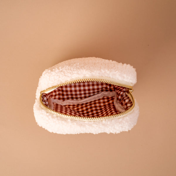 Introducing the Square Touchdown Teddy Teddy Pouch by The Darling Effect—a small, white, fluffy pouch made from soft sherpa fabric and finished with a gold zipper. Seen from above, its interior features a stylish brown and white checkered lining, making it an ideal addition to your accessory collection or the perfect match for other teddy pouches.