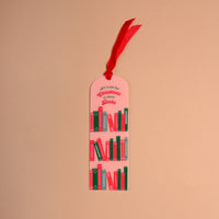 All I Want for Christmas is More Books Acrylic Bookmark in pink, featuring rows of illustrated books, the text all I want for Christmas is more Books, and a red velvet ribbon at the top.