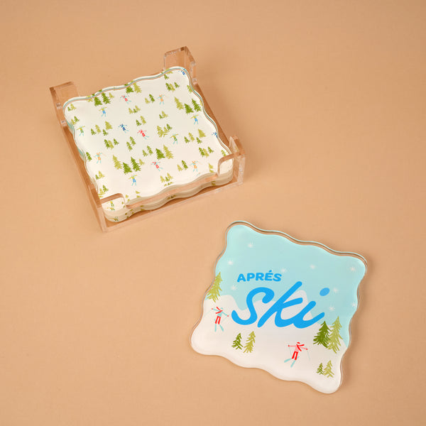 Aprés Ski Table Talk Acrylic Coaster Set featuring scalloped coasters in a clear holder, with artistic illustrations of skiers and pine trees and the text Après Ski on one piece.