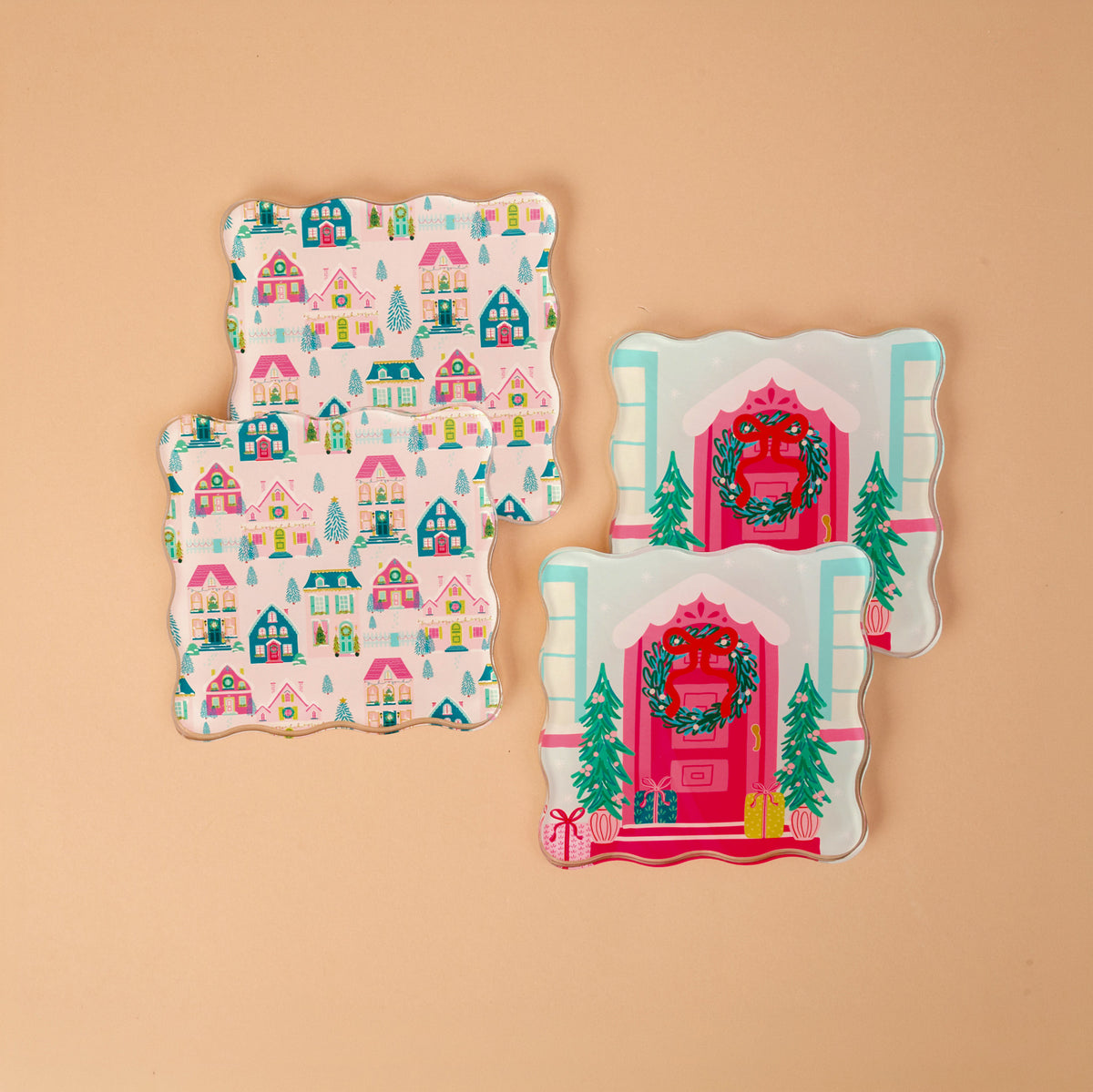 Sugarplum Lane Table Talk Acrylic Coaster Set featuring four square coasters with wavy edges: two with a repeating holiday house pattern and two with a single house featuring a wreath on the front door.
