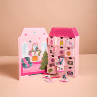 Adoring Ornaments Ornament Advent Calendar shaped like a house, featuring twelve numbered drawers, three of which are open to reveal hanging holiday décor.