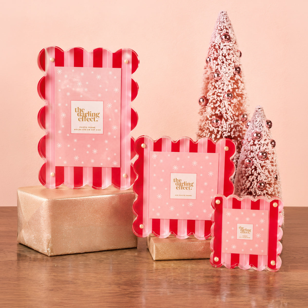 Three Peppermint Stripes Little Moments Acrylic Picture Frames with red and pink stripes and white snowflake accents, displayed next to two pink decorative Christmas trees on gold-wrapped boxes.