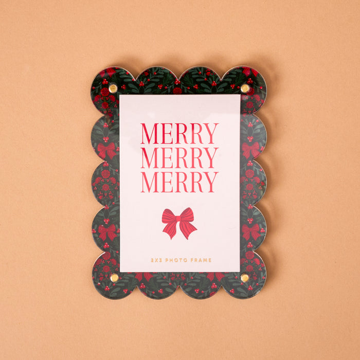 A Merry Moment Mini Acrylic Picture Frame Magnet with a scalloped edge, Christmas holly and red bow pattern, and a card reading Merry Merry Merry.