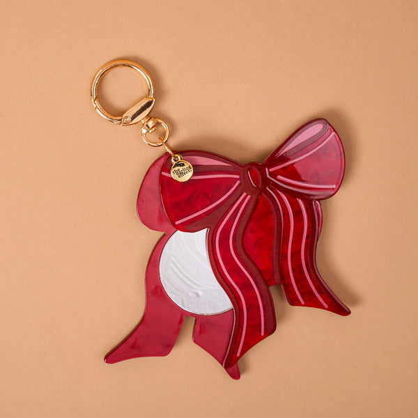 Red Bow Mini Mirror Bag Charm featuring a red acrylic bow-shaped mirror with a gold-toned clip.
