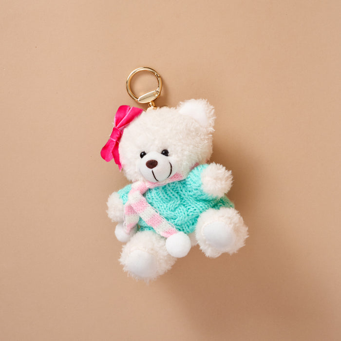 Arctic Angel Teddy Bear Bag Charm: a white teddy bear charm wearing a teal sweater, a pink and white striped scarf, and a pink bow on its head, attached to a gold key ring.