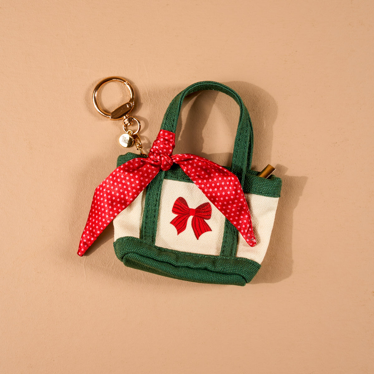 Merry Little Bow Tiny Tote Bag Charm in cream and green canvas, featuring a red bow embroidery and a red polka-dot scarf.