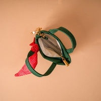A Merry Little Bow Tiny Tote Bag Charm featuring a miniature forest green canvas tote with a red and white polka dot ribbon tied to the handle.
