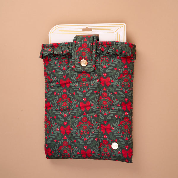 A Merry Moment Book Cover featuring a green quilted pattern with red bows, berries, and evergreen sprigs, finished with a ruffled top edge and a snap-button closure.