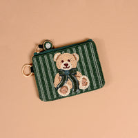 Teddy Bear Theo Handcrafted Beaded Pouch featuring a handcrafted beaded teddy bear design on a green and black striped background.