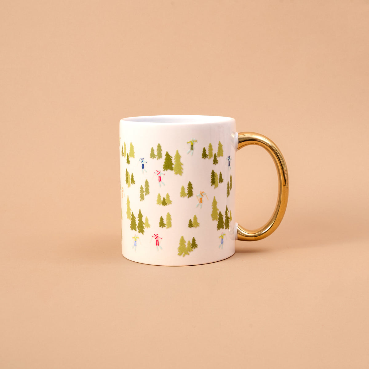 Aprés Ski 11 oz Cozy Cute Ceramic Mug in white with a gold handle, decorated with a pattern of evergreen trees and tiny figures skiing for a cozy moment.