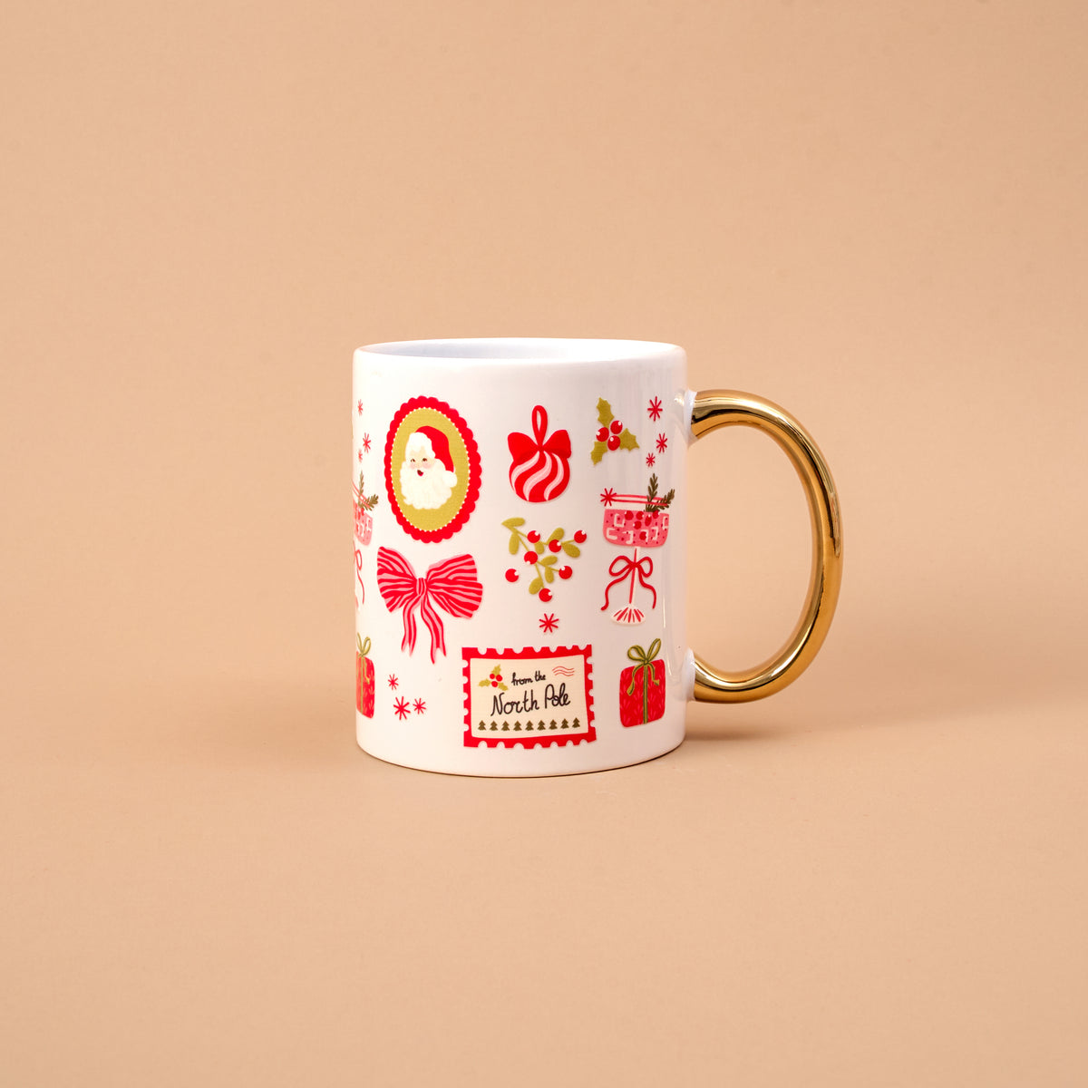 The Mistletoe Magic 11 oz Cozy Cute Ceramic Mug is a white ceramic cup with a gold handle and festive accents, featuring a From the North Pole label for a cozy holiday feel.