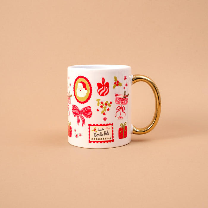 The Mistletoe Magic 11 oz Cozy Cute Ceramic Mug is a white ceramic cup with a gold handle and festive accents, featuring a From the North Pole label for a cozy holiday feel.
