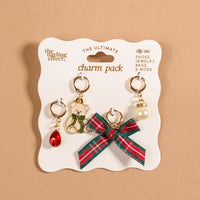 Comfort & Joy The Ultimate Charm Pack featuring four holiday-themed accessory charms on a display card, including a red gem, a teddy bear, a plaid bow, and a faux pearl.