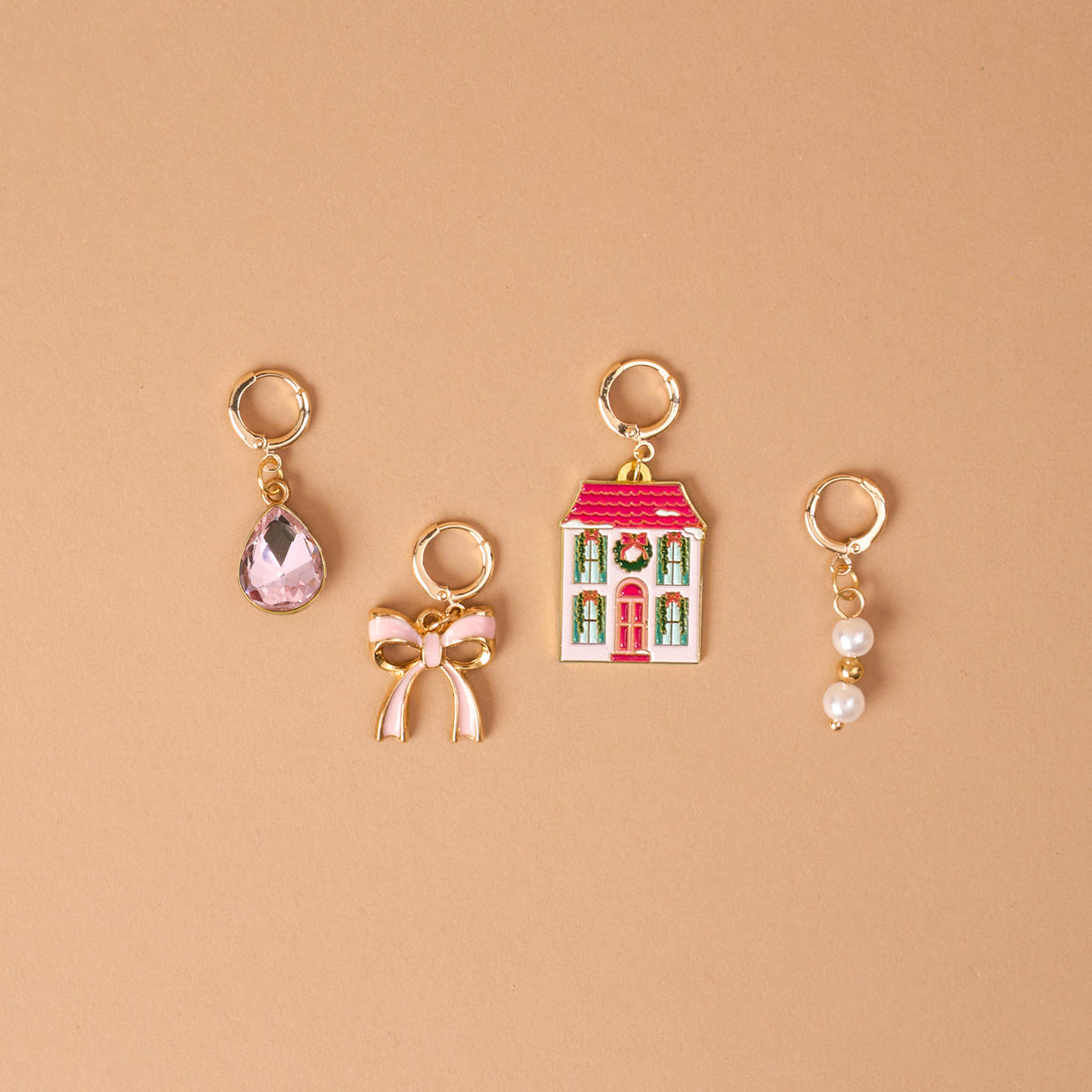 Twinkle Town The Ultimate Charm Pack featuring four gold hoop charms: a pink teardrop gem, a pink bow, a Christmas-themed house, and two small pearls.