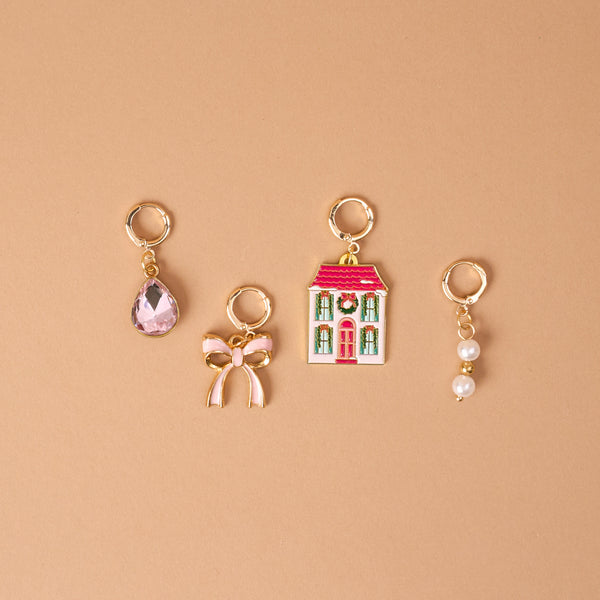 Twinkle Town The Ultimate Charm Pack featuring four gold hoop charms: a pink teardrop gem, a pink bow, a Christmas-themed house, and two small pearls.