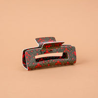 A Merry Moment Claw Clip featuring a rectangular design with a dark green floral and berry pattern for a strong hold.