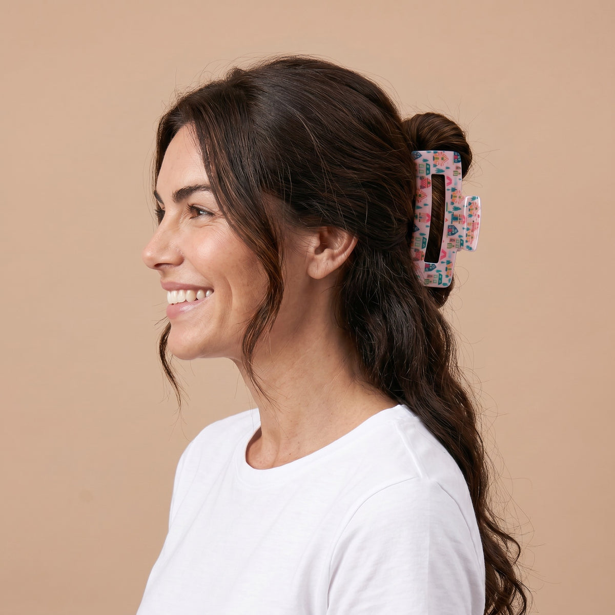 A person wearing a Sugarplum Lane Claw Clip by The Darling Effect, decorated with small houses and trees.