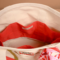Interior view of the Peppermint Stripes The Darling Canvas Tote Bag, featuring a red lining, multiple pockets, and a rectangular patch reading from the North Pole.