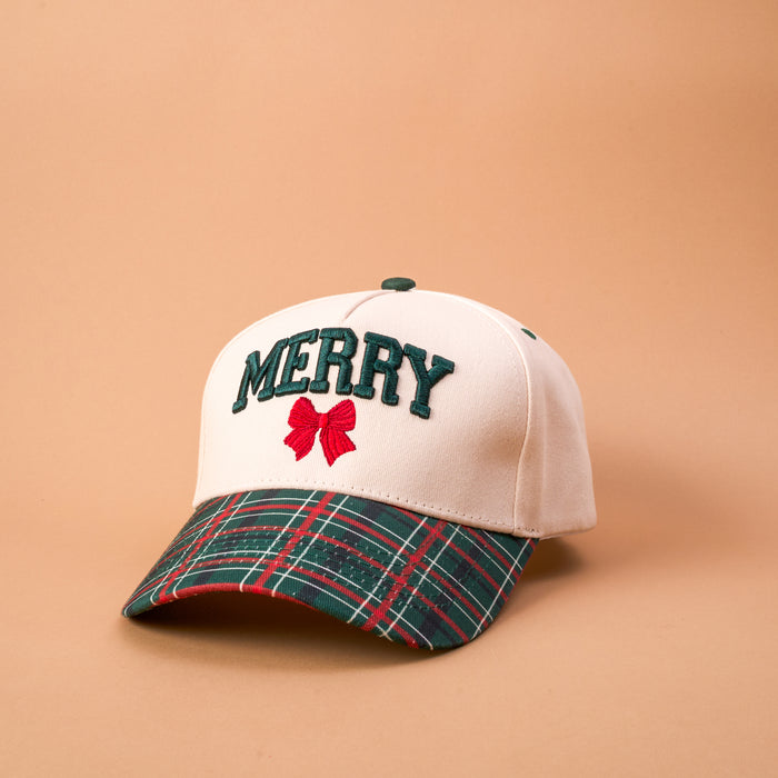 The Darling Effect Merry Classic Canvas Hat is a beige baseball cap with a green plaid brim, embroidered with the word MERRY in dark green letters above a small red bow.