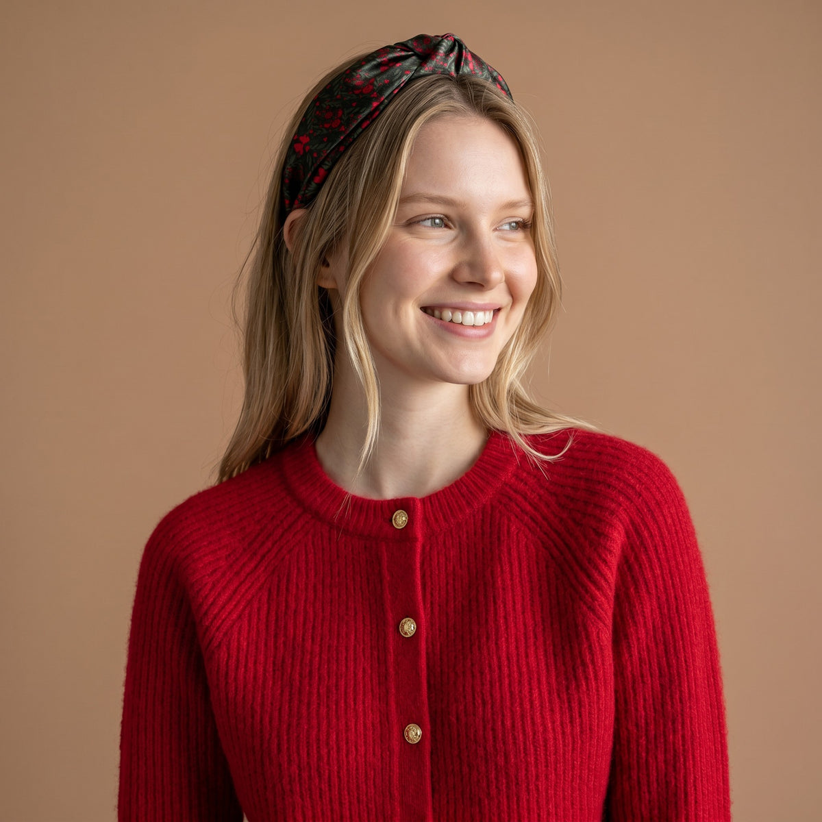 A woman wears The Darling Effect A Merry Moment Classic Twist Headband, featuring a dark patterned knotted twist design.
