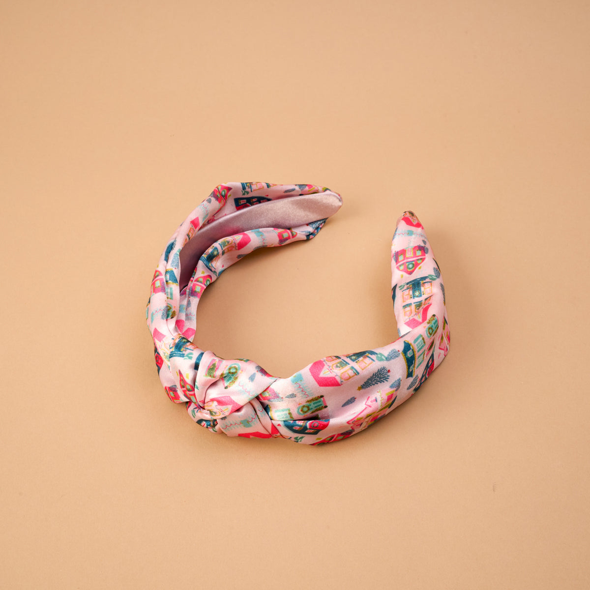 Sugarplum Lane Classic Twist Headband in pink fabric featuring a whimsical print of small houses and trees.