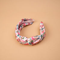 Sugarplum Lane Classic Twist Headband in pink fabric featuring a whimsical print of small houses and trees.