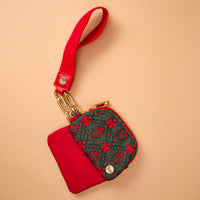 The Darling Effect A Merry Moment Dynamic Duo Pouch Wristlet in luxe red and dark green floral with a red strap and gold hardware, perfect for hands-free carry.