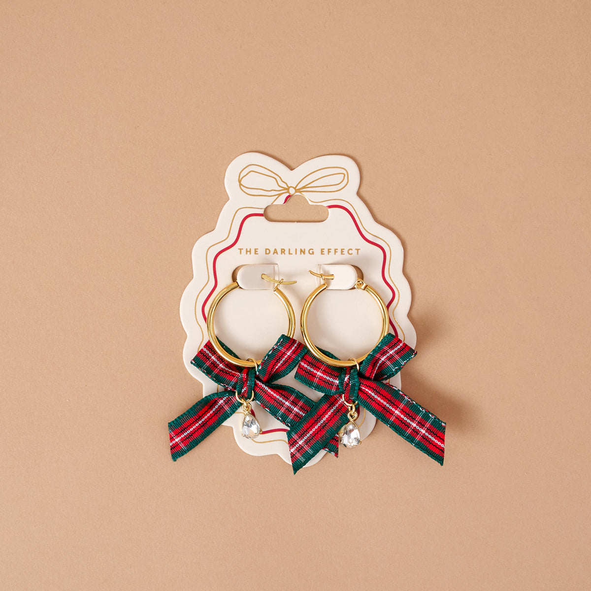 Dressed in Plaid Signature Hoop Earrings featuring lightweight gold hoops on a display card, decorated with red and green plaid ribbon bows and dangling teardrop crystals.
