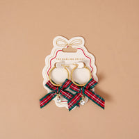 Dressed in Plaid Signature Hoop Earrings featuring lightweight gold hoops on a display card, decorated with red and green plaid ribbon bows and dangling teardrop crystals.