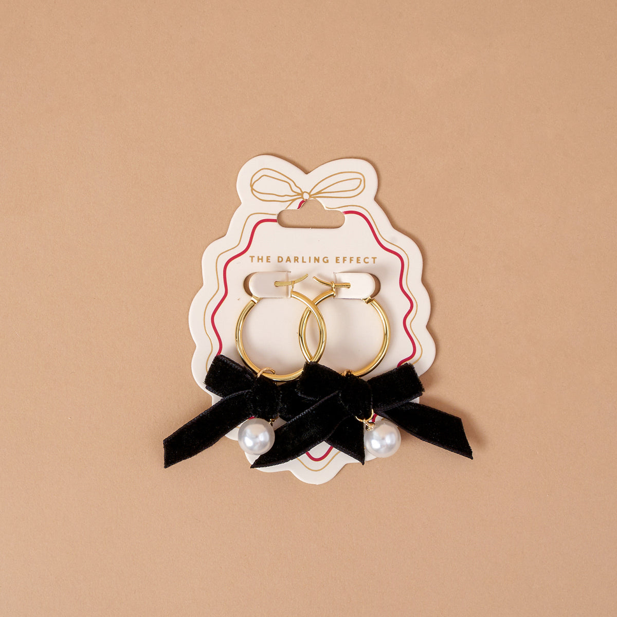 Midnight Velvet Signature Hoop Earrings featuring lightweight gold hoops on a display card, each decorated with a black ribbon bow and a hanging white pearl bead.
