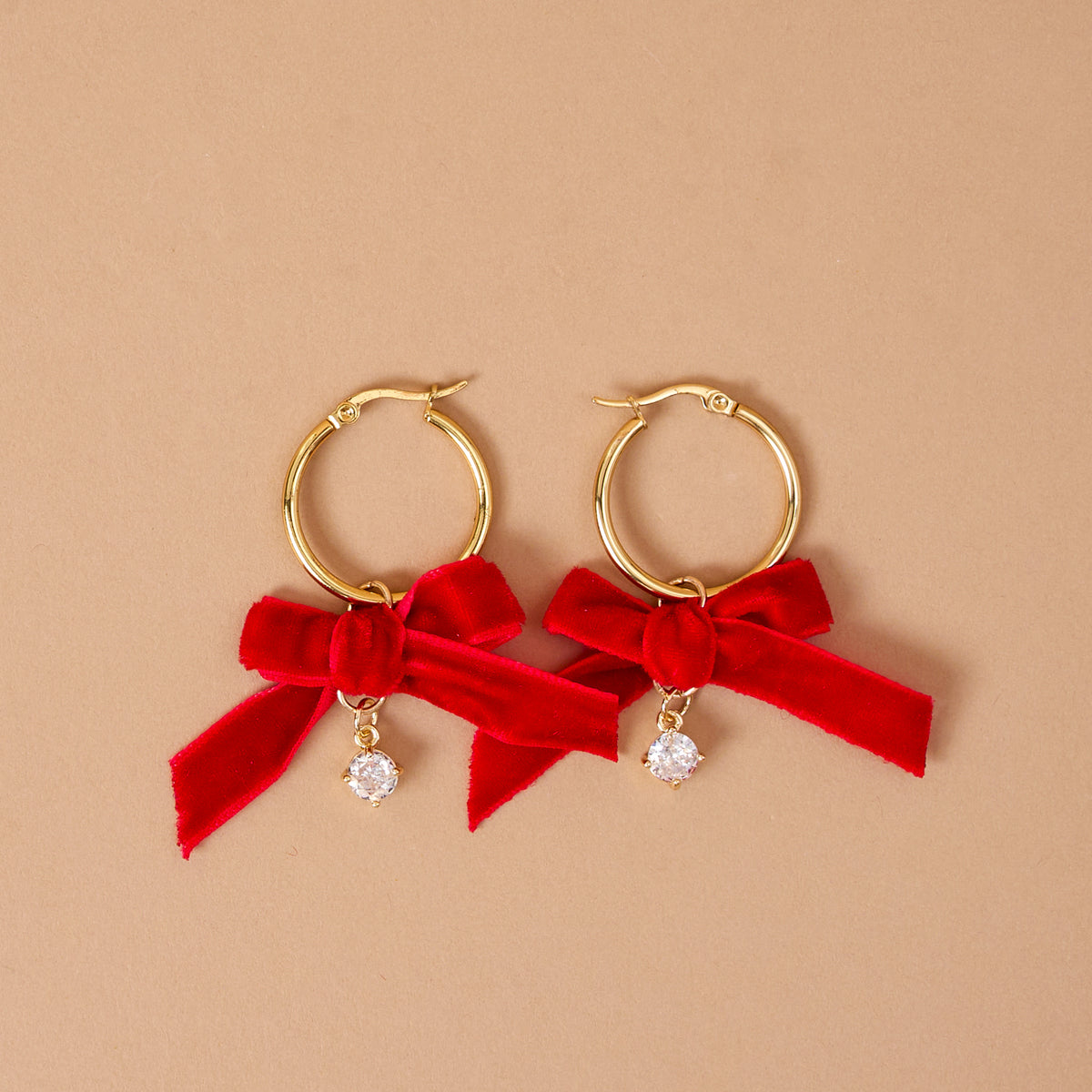 Ruby Ribbon Signature Hoop Earrings featuring lightweight gold hoops accented with red ribbon bows and small dangling crystals.