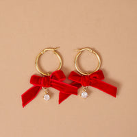 Ruby Ribbon Signature Hoop Earrings featuring lightweight gold hoops accented with red ribbon bows and small dangling crystals.