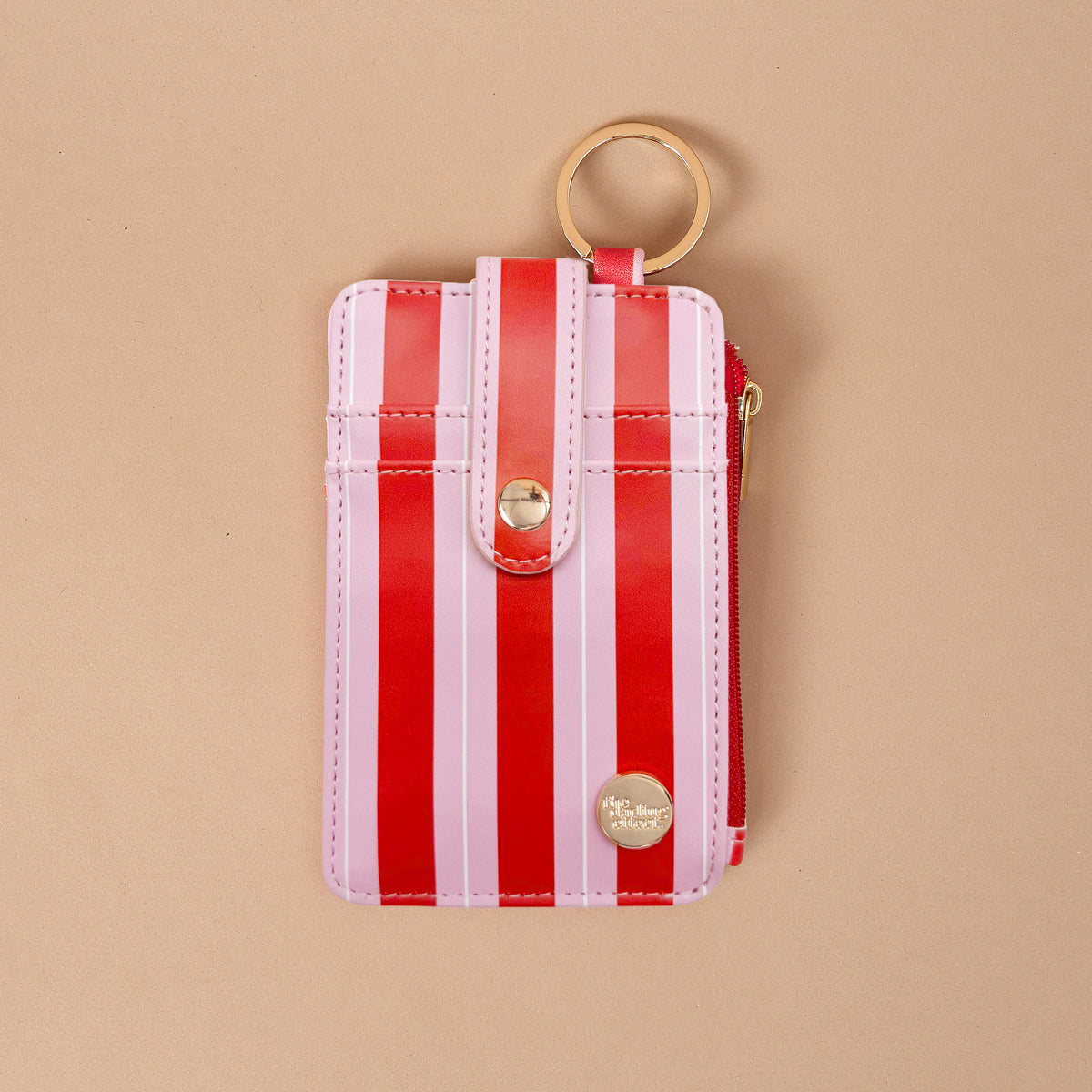 The Peppermint Stripes Keychain Wallet is a small vertical wallet with a red and pink striped pattern, a snap-button closure, and a gold keyring on this slim design.