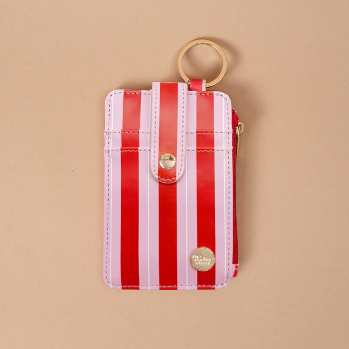 The Peppermint Stripes Keychain Wallet is a small vertical wallet with a red and pink striped pattern, a snap-button closure, and a gold keyring on this slim design.