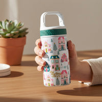 A hand holds a Sugarplum Lane 6 oz Lil’ Bitty Bottle, a petite insulated bottle patterned with illustrations of colorful houses, pine trees, and a picket fence.