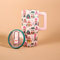 The Darling Effect Sugarplum Lane 20 oz Lifestyle Flip Straw Tumbler in light pink with a pattern of colorful, whimsical houses, shown with its lid removed.