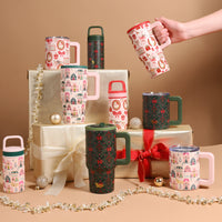 A hand holds a Sugarplum Lane 20 oz Lifestyle Flip Straw Tumbler above several other festive travel mugs, arranged around wrapped gold gift boxes.