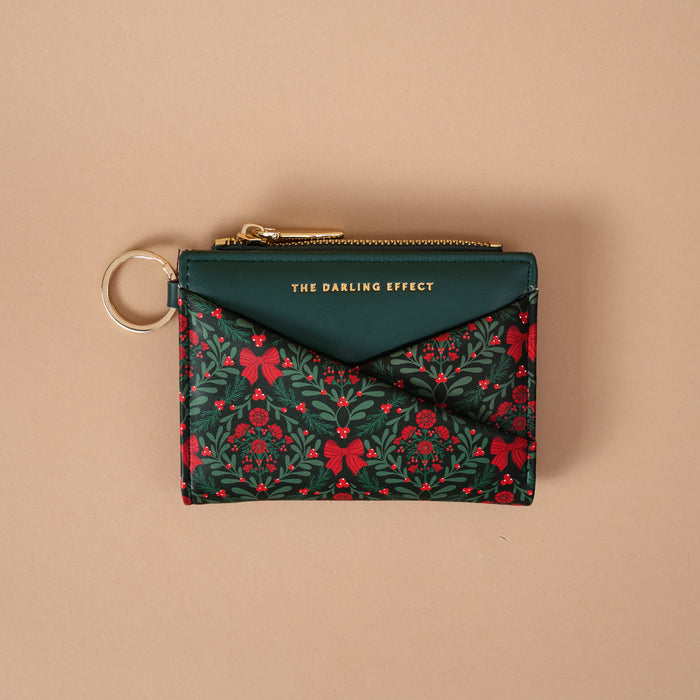 A Merry Moment Luxe Pocket Wallet by The Darling Effect, featuring a dark green and red holiday-themed floral print, a gold keyring, and a dark green flap pocket.